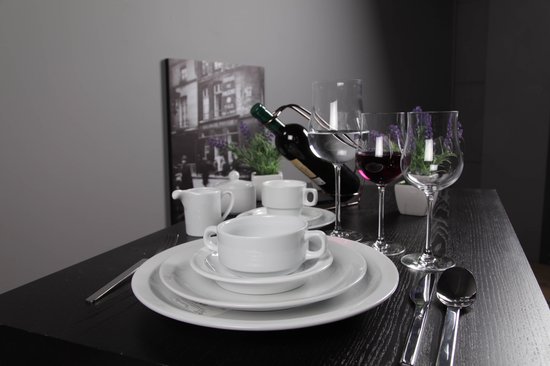 Tafel gedekt met servies, wijnglazen, een fles rode wijn, en een melkkannetje.
