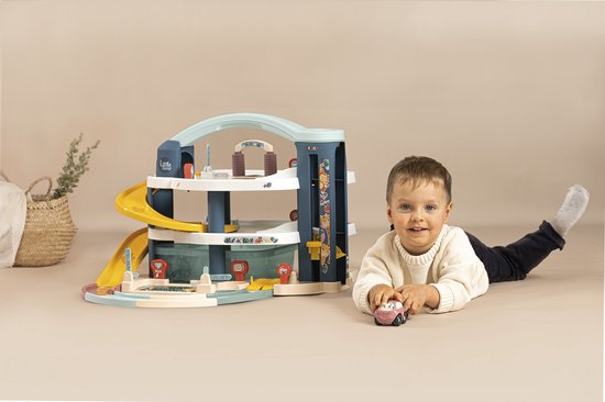 Jongen met een speelgoedgarage met gele glijbaan en een auto.