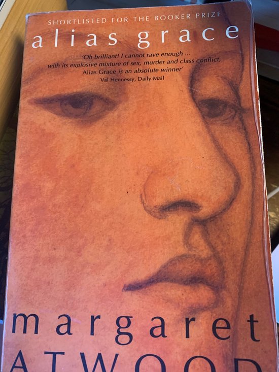 Boek "Alias Grace" door Margaret Atwood, met een oranje cover met het gezicht van een vrouw.