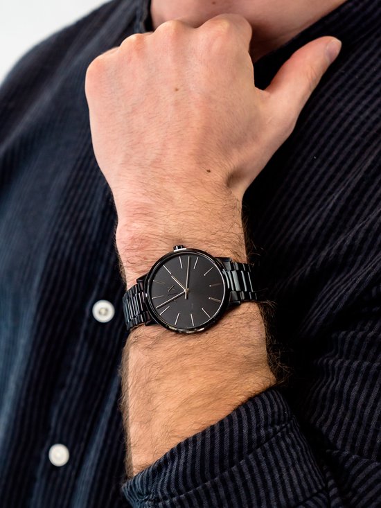 Armani Exchange zwart herenhorloge om een pols, met donker gestreept overhemd.