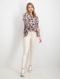 Model in lichte, skinny jeans met rafels aan de onderkant en beige sneakers.