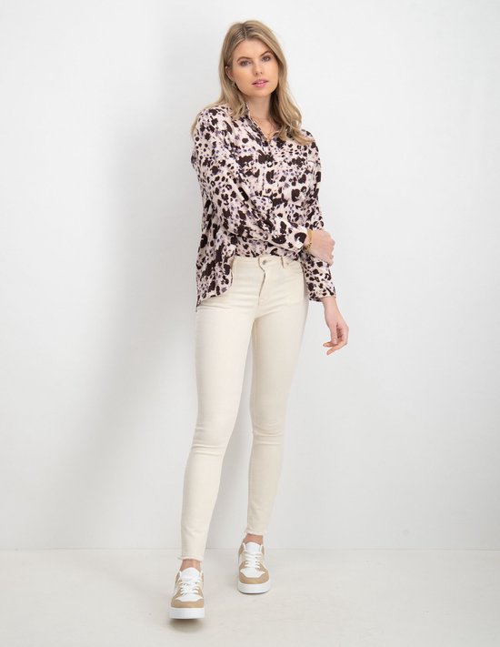 Model in lichte, skinny jeans met rafels aan de onderkant en beige sneakers.