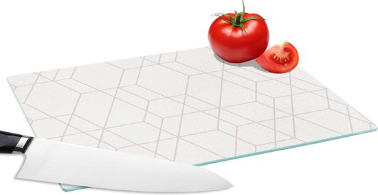 Planchette en verre avec motif mosaïque géométrique rose pâle, avec un couteau, une tomate et une tranche de tomate.
