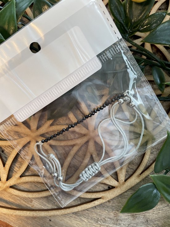 Zwarte facet geslepen kristallen armband met verstelbaar zilverkleurig koord, in verpakking.