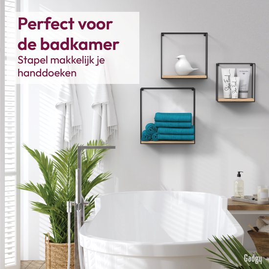 Badkamerinterieur met drie wandrekken, gevuld met handdoeken, een plant en cosmetica.