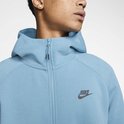Close-up van een lichtblauwe Nike Tech Fleece hoody met zwarte Nike logo