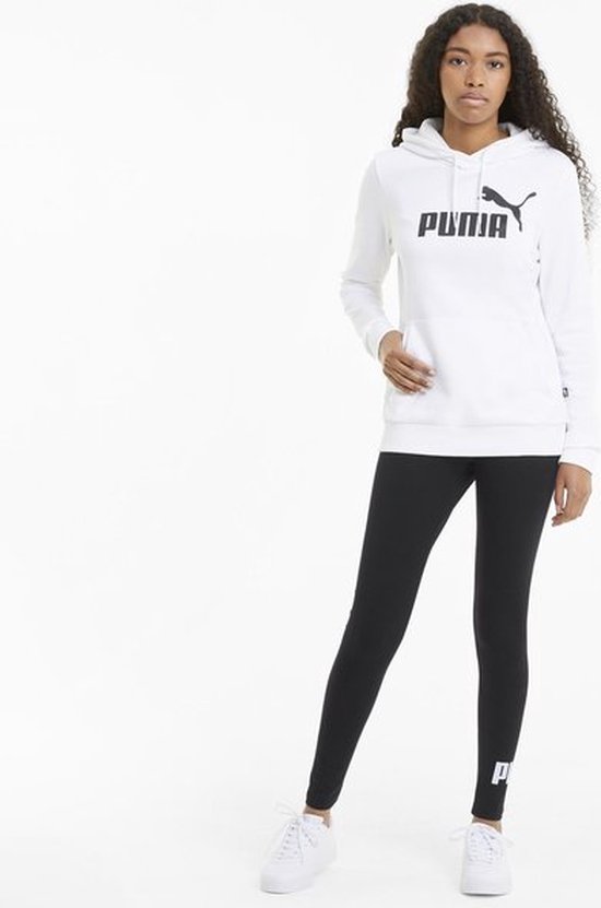 Model in zwarte PUMA legging met wit logo op de linker broekspijp en een witte PUMA hoodie.