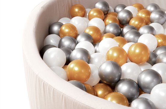 Gouden, zilveren en parelmoer ballen in een taupe grijze ballenbak, close-up van de rand.