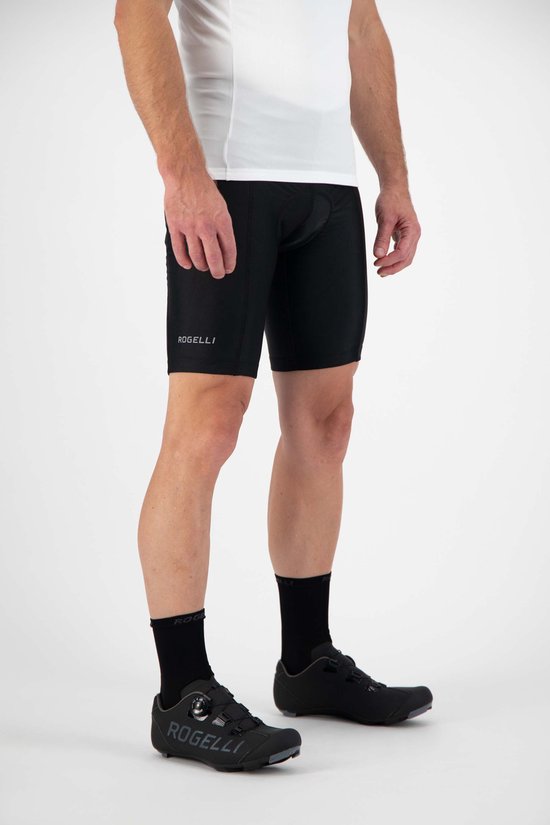 Man in een wit wielershirt en zwarte fietsbroek, met zwarte sokken en fietsschoenen. "ROGELLI" logo op broek.