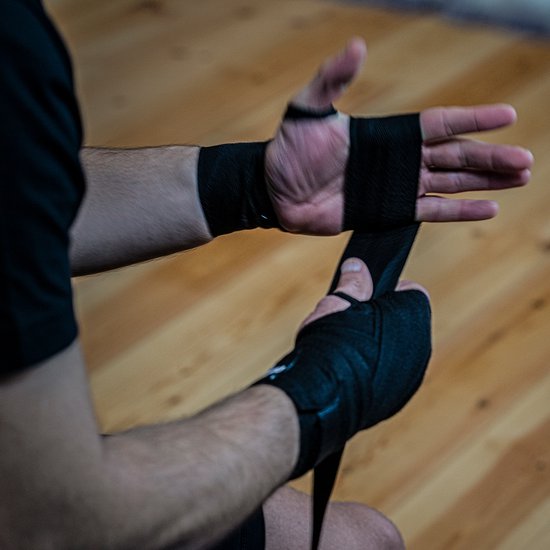 Een persoon die zijn handen wikkelt met zwarte bok bandages.