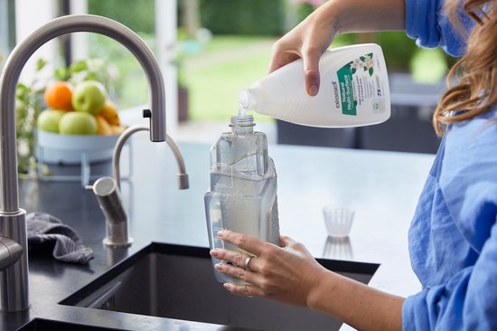 Handen vullen een reservoir van een Bissell Crosswave C3 Select steelstofzuiger met schoonmaakvloeistof.