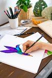 Hand tekent een kolibrie met paarse, blauwe en groene potloden.