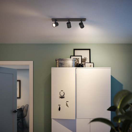 Zwarte Philips Hue plafondlamp met drie spotjes boven een witte kast.