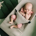 Baby ligt in wipstoel met wafelstof. Baby draagt roze broekje en topje met ruches.