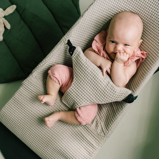 Baby ligt in wipstoel met wafelstof. Baby draagt roze broekje en topje met ruches.
