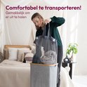 Vrouw in donkergroene blouse en grijze jeans haalt een grijze waszak uit de wasmand met bamboe deksel. Tekst: 'Comfortabel te transporteren!'.