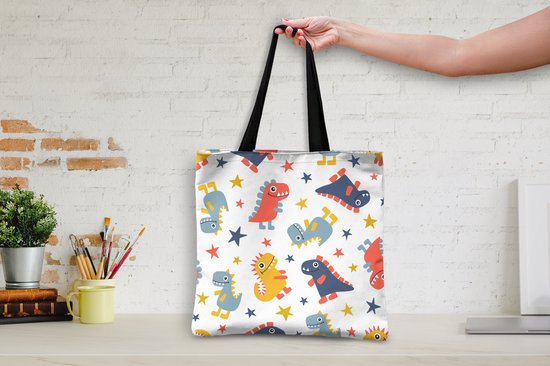 Sac blanc à motif de dinosaures et d'étoiles rouges, bleus et jaunes, exposé sur un bureau.