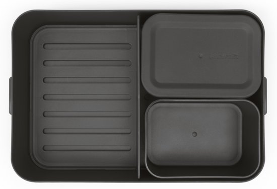 Top view van donkergrijze bento lunchbox met sandwich, fruit en salade.