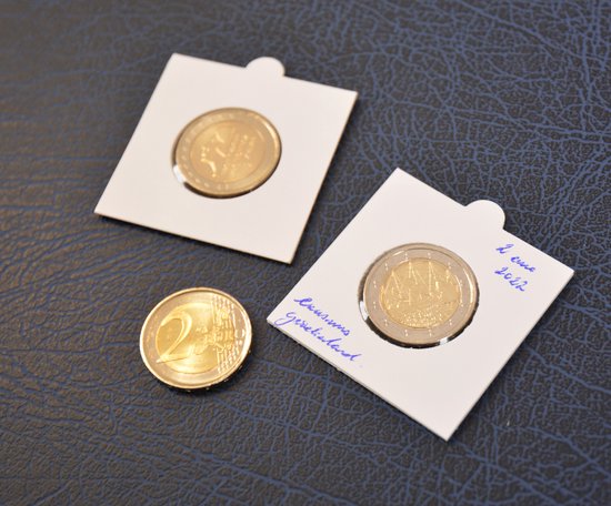 Twee witte munthouders van karton met 2 euro munten, met handgeschreven tekst.