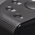 Detail van de bovenkant van een zwarte wekkerradio met een powerknop.