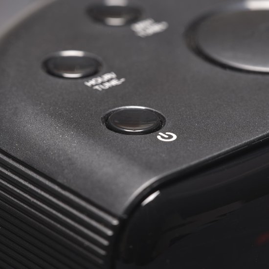 Detail van de bovenkant van een zwarte wekkerradio met een powerknop.