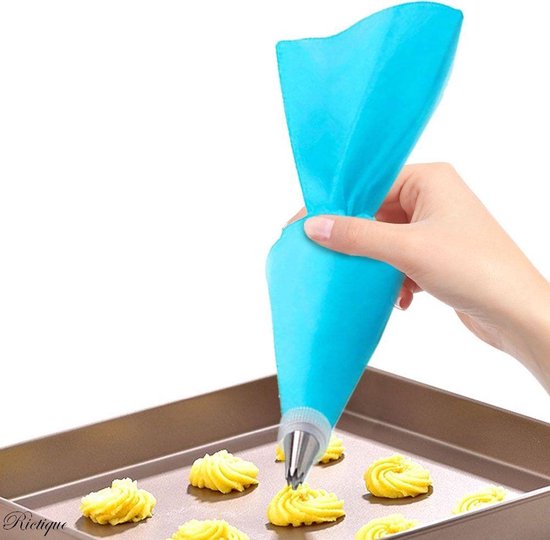 Een hand gebruikt een blauwe spuitzak om gele koekjes te versieren op een bakplaat.