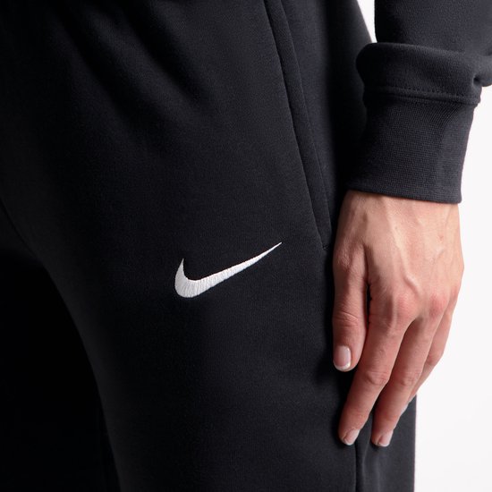 Close-up van een zwarte Nike trainingsbroek met geborduurd wit logo op de heup.