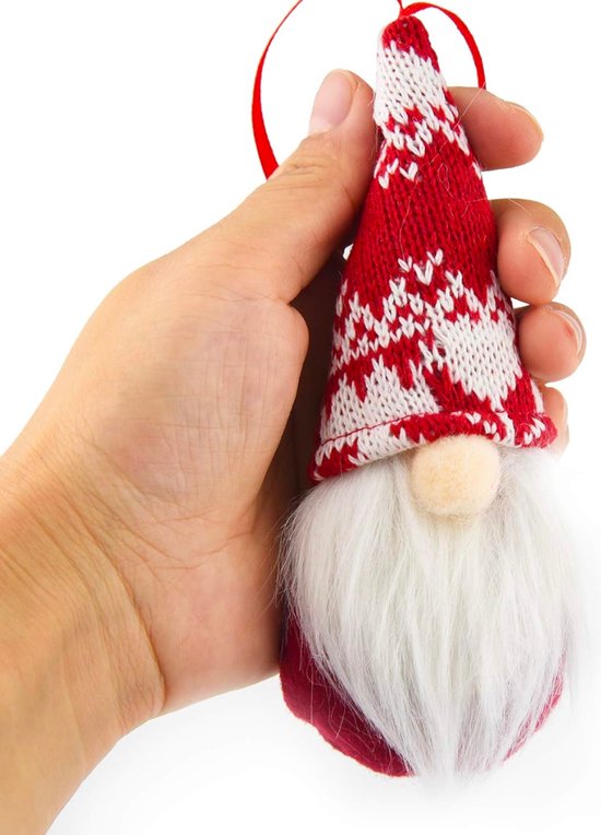 Main tenant un nain de Noël avec un bonnet tricoté rouge et blanc à motifs et une barbe blanche.