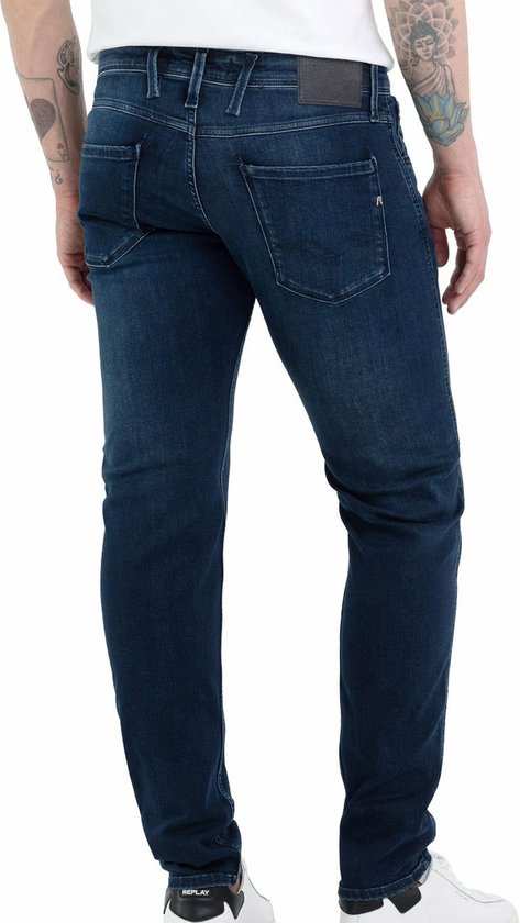 Achterkant van man in donkerblauwe spijkerbroek en witte sneakers.
