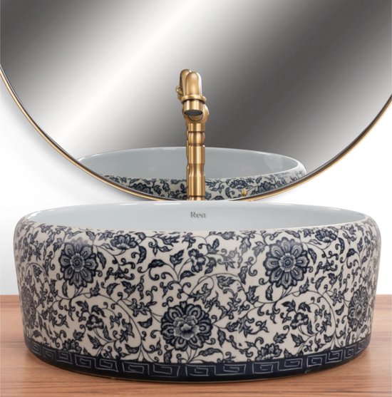 Lavabo blanc à motif floral bleu et blanc et robinet en laiton. Modèle rond, 40 cm de large.
