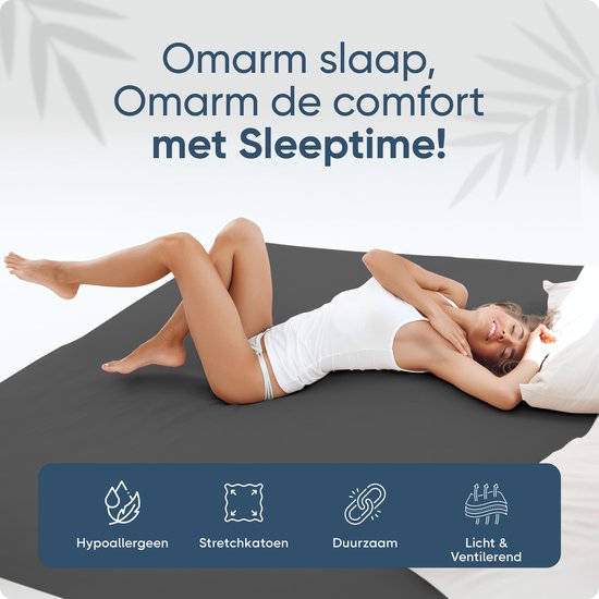 Vrouw ligt op een donkergrijs hoeslaken. Hypoallergeen, stretch, duurzaam en ventilerend.