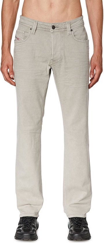 Model in een lichtgrijze, skinny fit Diesel jeans met beige stiksels. De jeans heeft een normale taille en is gedragen met zwarte schoenen.