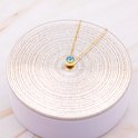 Gouden ketting met blauwe zirkonia op display met gouden cirkels.