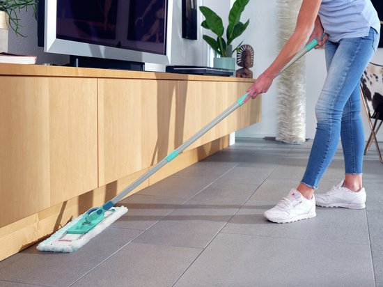 Femme en jean et baskets blanches utilisant la serpillière Leifheit Profi XL Micro Duo dans un intérieur moderne.