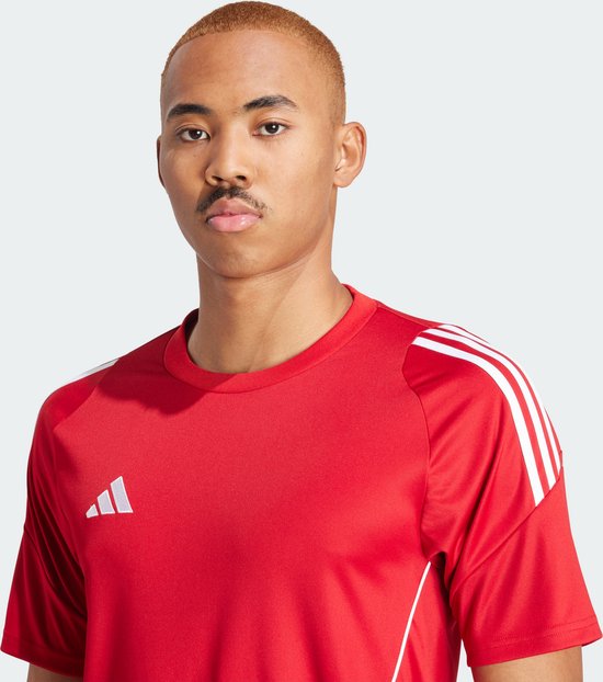 Close-up van een man in een rood adidas sportshirt met witte strepen op de schouders.