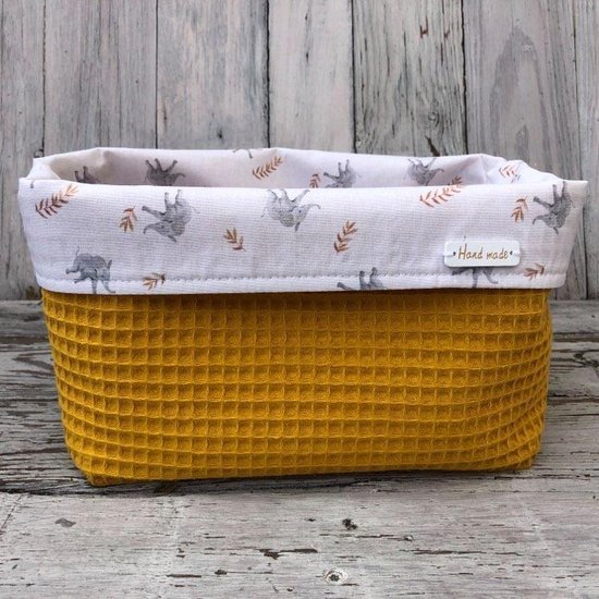 Okergeel mandje met wafeltextuur en een witte binnenkant met grijze olifantjes en takjes. "Hand made" label zichtbaar.