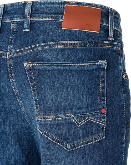 Achterkant van een blauwe jeans met een bruin lederen MAC JEANS label en geborduurde zakken.