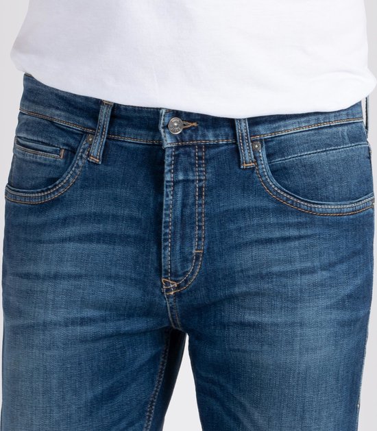 Detail van de voorkant van een donkerblauwe spijkerbroek met oranje stiksels.