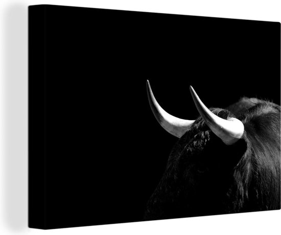 Canvas Schilderij Een foto van een zwarte stier tegen een zwarte achtergrond - zwart wit - 60x40 cm - Wanddecoratie