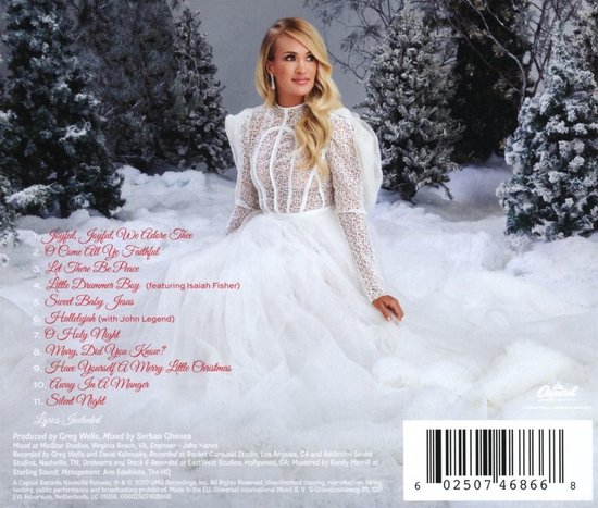 Carrie Underwood in een witte jurk, staand in de sneeuw. Tracklist van 'My Gift' album zichtbaar.