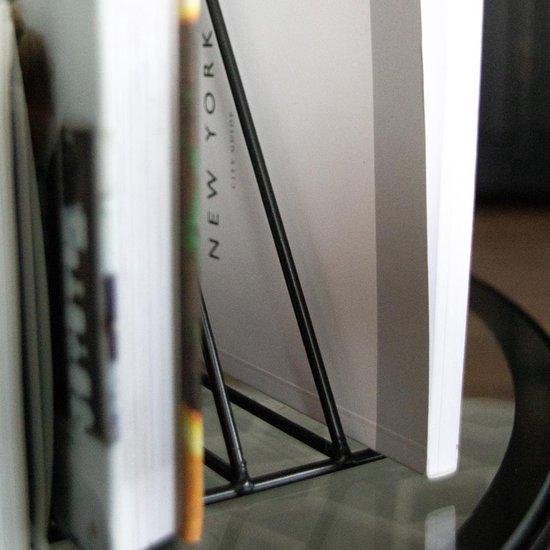 Close-up van een zwarte metalen tijdschriftenhouder met boeken, waaronder 'NEW YORK CITY GUIDE'.