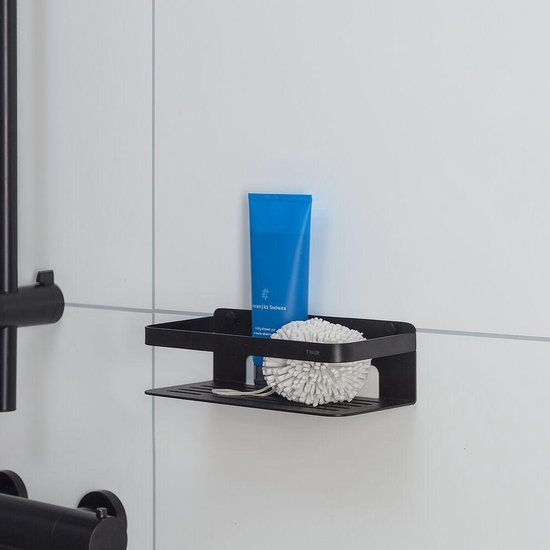 Zwart douche rekje aan een witte tegelmuur met blauwe tube douchegel en witte douchebol.