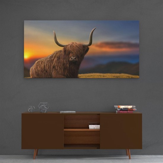 Impression sur toile d'une vache écossaise highland sur une colline, accrochée au-dessus d'un buffet avec des livres.