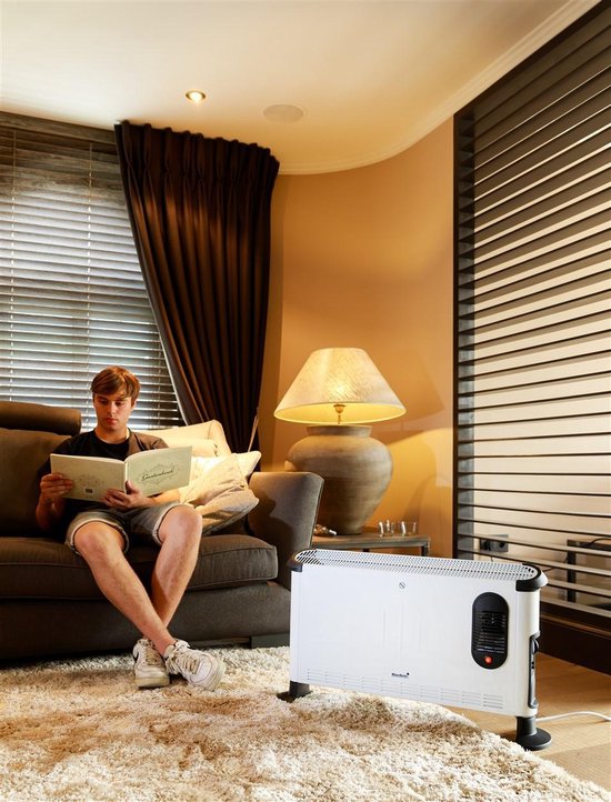 Witte elektrische convector verwarming met zwarte accenten, staand op een vloerkleed.