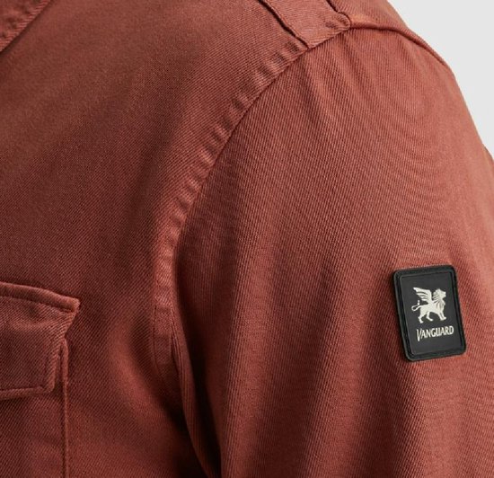 Detail van de schouder van een koraalrood overhemd met een vierkant logo patch 'Vanguard'.