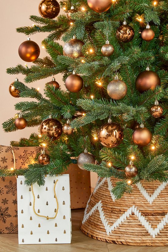 Kerstboom versierd met bruine en glitter kerstballen, met lichtjes, cadeaus en een mand.
