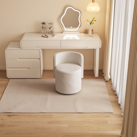 Lichtbeige, ronde kruk met gebogen rugleuning, geplaatst voor een witte kaptafel.
