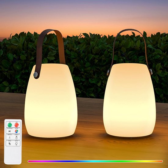 Deux lanternes LED portables blanches avec poignées en cuir marron sur une table en bois au coucher du soleil, avec une télécommande.