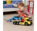 Jongen speelt met gele takelwagen met rode kraan die een blauwe Ford Mustang optilt.
