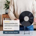 Een persoon toont een LP op een zwarte displaystandaard.